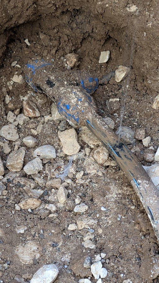 Piccolo getto d’acqua dalla tubazione in polietilene messa a vista nello scavo