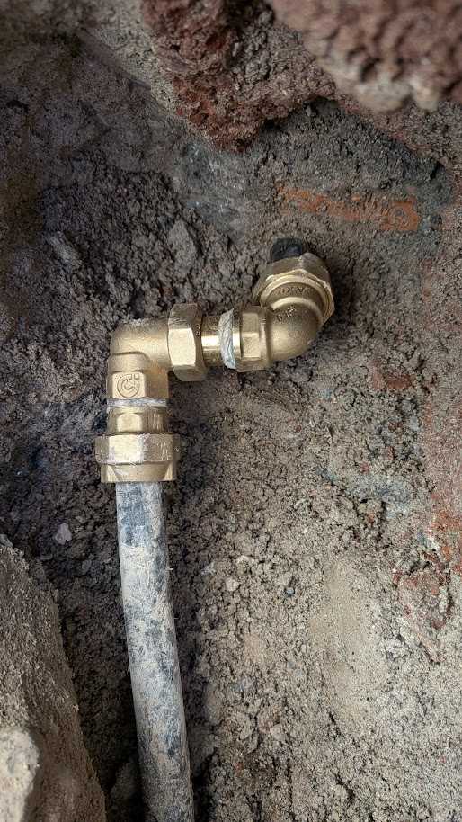 Raccordi in ottone sulla tubazione in polietilene riparata nello spazio ristretto della parete